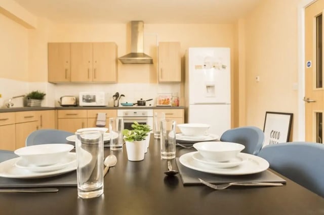Table setting with chairs and kitchen area kitchen at Okeford House in Bournemouth Student Accommodation