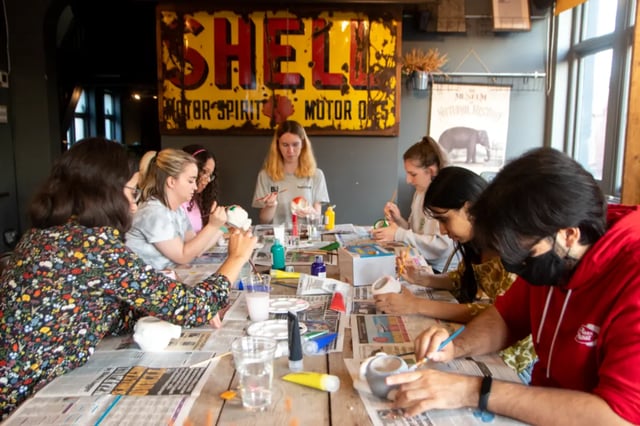 Students painting pottery at a table communal space at Okeford House in Bournemouth Student Accommodation