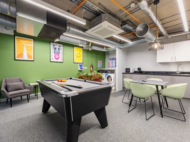 Pool table chairs washing machines kitchen area Common room at Venue Studios in London Student Accommodation