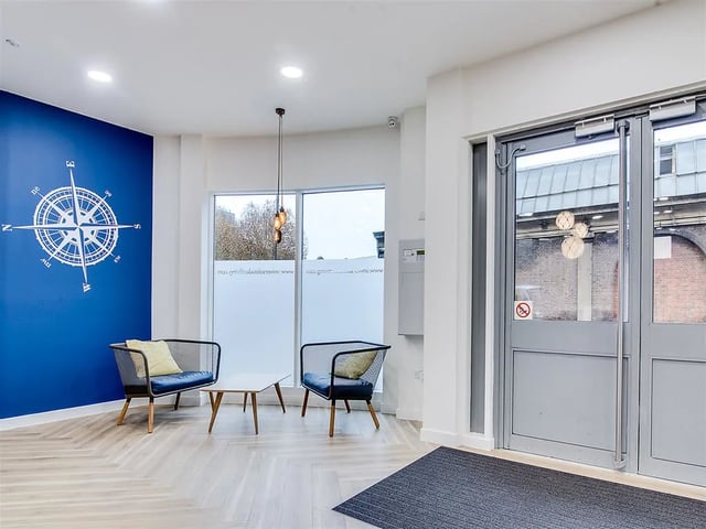 Two chairs a table and compass wall art communal area at New Orient House in London Student Accommodation