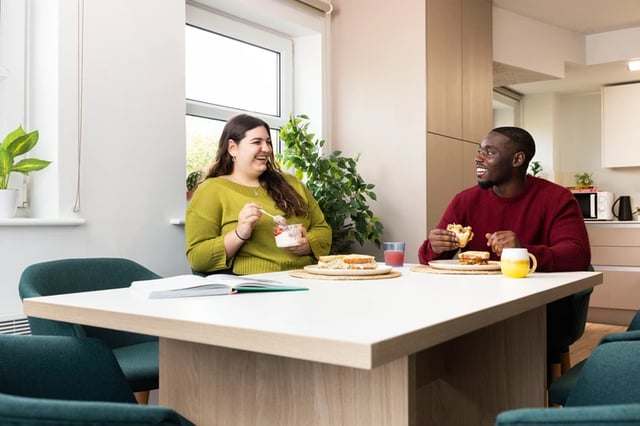 Students eating at table with food kitchen area at Cedar House in Liverpool Student Accommodation