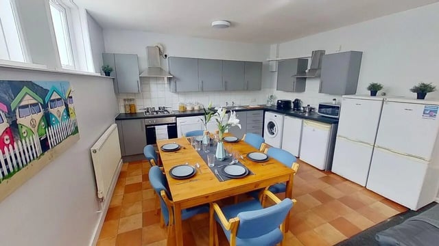 Wooden table with blue chairs kitchen counter appliances kitchen at 6 Albert Square in Nottingham Student Accommodation