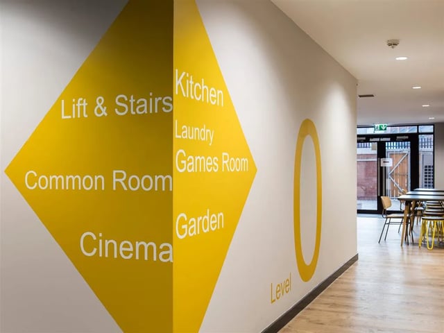 Yellow directional signage wall common room exterior at Botanic Studios in Belfast Student Accommodation