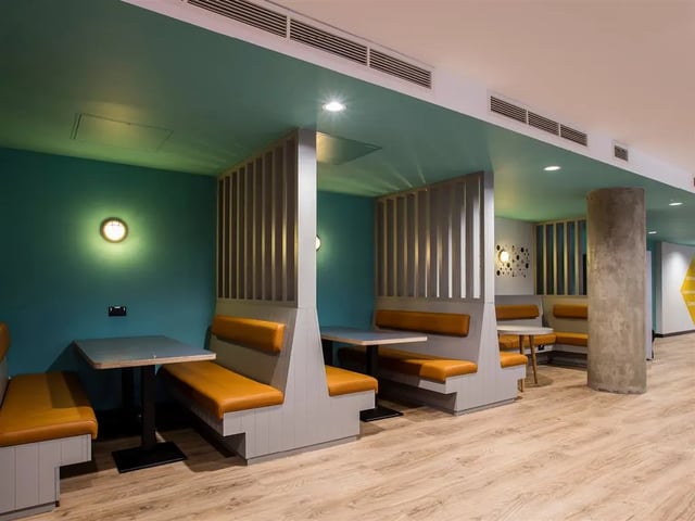 Student accommodation booths with tables and seating lounge area at Botanic Studios in Belfast Student Accommodation