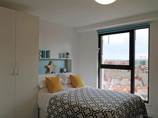 Wardrobe bed with yellow pillows and city view bedroom at Botanic Studios in Belfast Student Accommodation