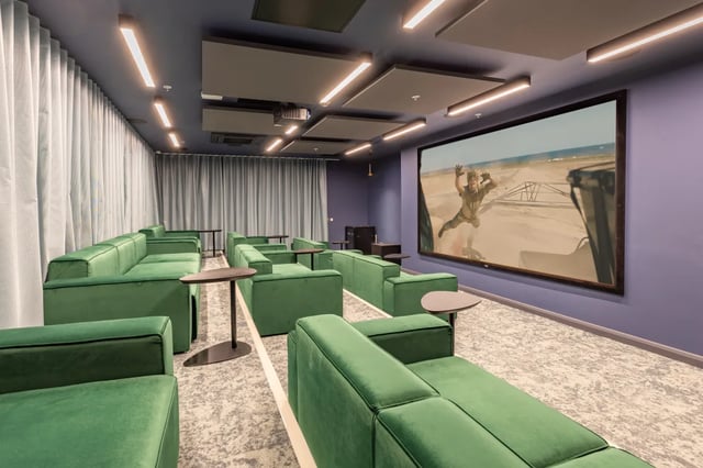 Green couches facing large cinema screen entertainment room at Winfield Court in Nottingham Student Accommodation