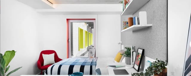 Bed desk red chair and plants bedroom at Scape Guildford in Guildford Student Accommodation