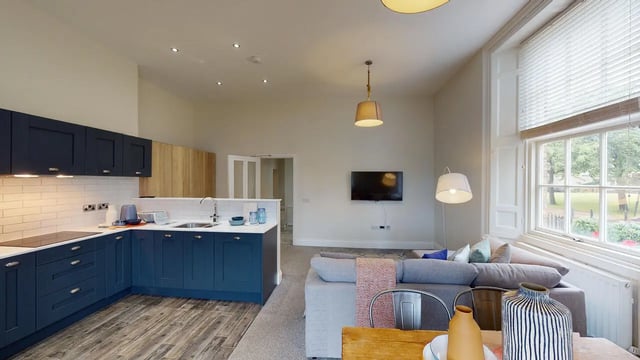 Modern blue kitchen and living area with sofa. at Picton Manor in Newcastle Upon Tyne Student Accommodation