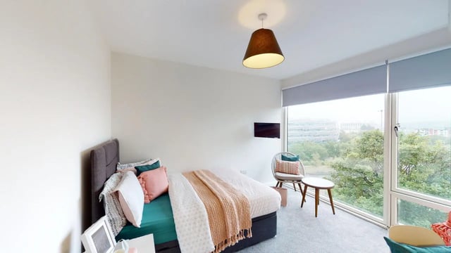Bed with pillows throws and chair by window bedroom at Picton Manor in Newcastle Upon Tyne Student Accommodation