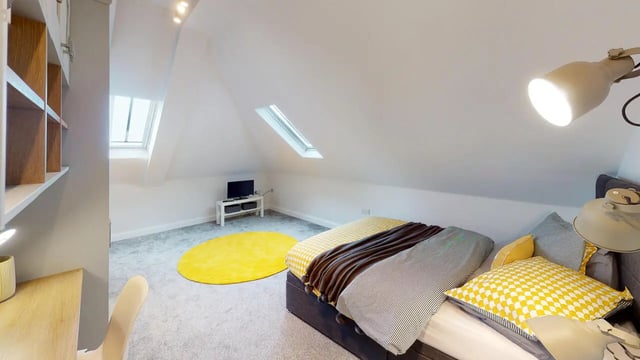 Bed TV yellow rug bookshelves desk chair bedroom at Picton Manor in Newcastle Upon Tyne Student Accommodation