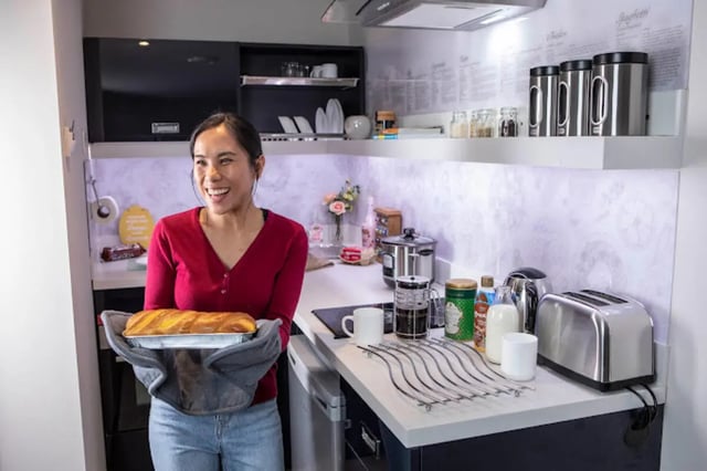 Woman holding baked bread in modern kitchen at Reynard House in Leicester Student Accommodation