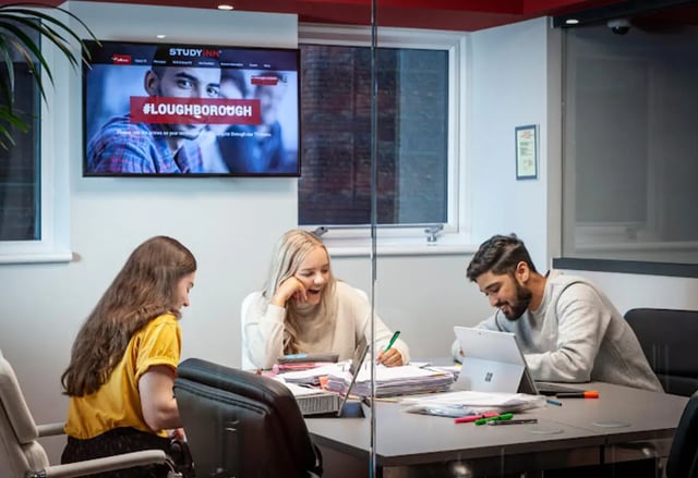 Students study at a table with laptops and papers study area at Study Inn Loughborough - Lemyngton Street in Loughborough Student Accommodation