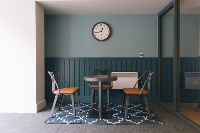 Table chairs rug clock heating living room at Picturehouse Apartments in Exeter Student Accommodation