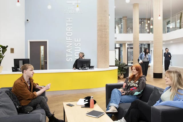Students sit on couches by yellow reception area communal space at Staniforth House in Birmingham Student Accommodation
