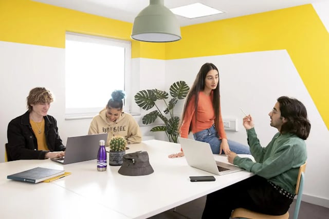 Students collaborating around a table with laptops study area at Harriet Martineau in Birmingham Student Accommodation