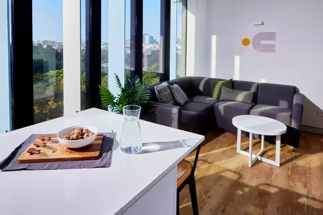 Dark sectional sofa coffee table and dining area living room at Scape Quay in Sydney Student Accommodation