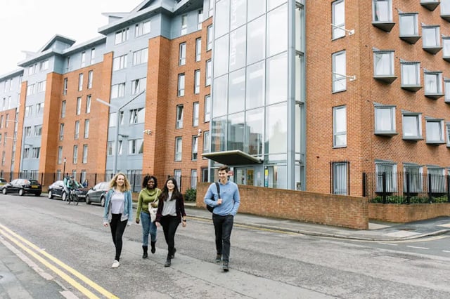 Students walking past brick student accommodation building exterior at Queen's Park House in Coventry Student Accommodation