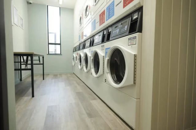 Row of washing machines with table laundry area at The Old Fire Station - Birmingham in Birmingham Student Accommodation