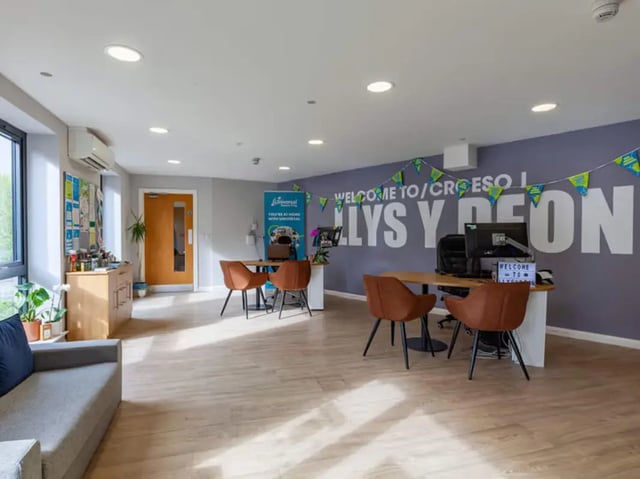 Reception area with desks chairs and welcome sign at Llys Y Deon in Bangor Student Accommodation