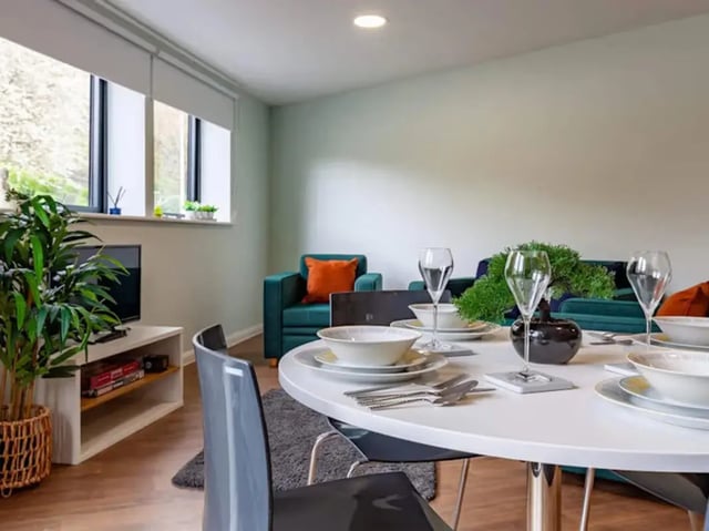 Table with place settings and chairs living room at Llys Y Deon in Bangor Student Accommodation