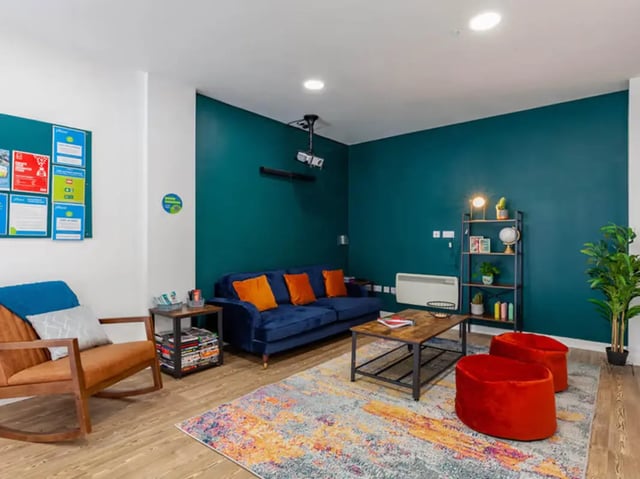 Blue sofa orange pillows and rocking chair living room at Neuadd Kyffin in Bangor Student Accommodation