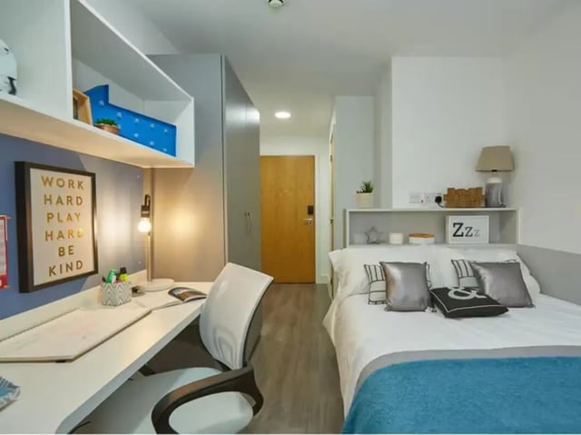 Desk bed with blue blanket and pillows bedroom at Collegelands in Glasgow Student Accommodation