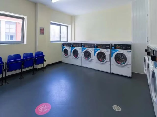 Washing machines and blue seats laundry room at Collegelands in Glasgow Student Accommodation