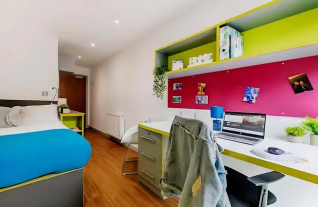 Bed desk with laptop and bright accent wall Bedroom at The Boulevard in York Student Accommodation