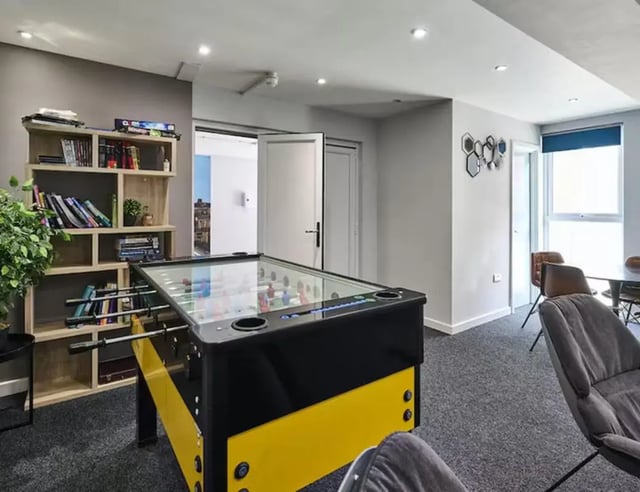Foosball table bookshelf chairs common area at The Boulevard in York Student Accommodation