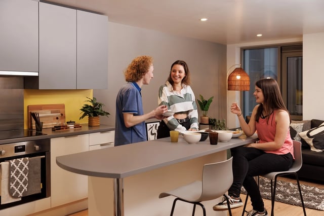Students gathered around kitchen island eating food kitchen at Horizon Heights in Liverpool Student Accommodation