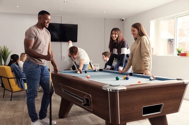 Students play pool in a common room. at Atlantic Point in Liverpool Student Accommodation