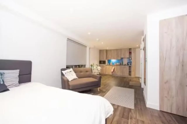 Bed sofa kitchen cabinetry and wooden door living room at Edge Apartments in Birmingham Student Accommodation