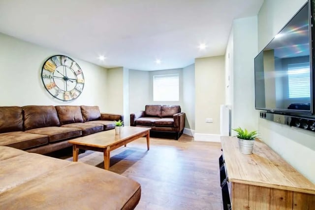 Brown sofas coffee table wall clock living room at 131 Hyde Park in Leeds Student Accommodation