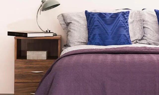 Bed with purple blanket blue pillow and nightstand bedroom at Claremont House in Glasgow Student Accommodation