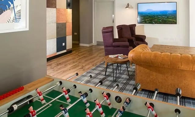 Foosball table with sofas armchairs television living room at Claremont House in Glasgow Student Accommodation