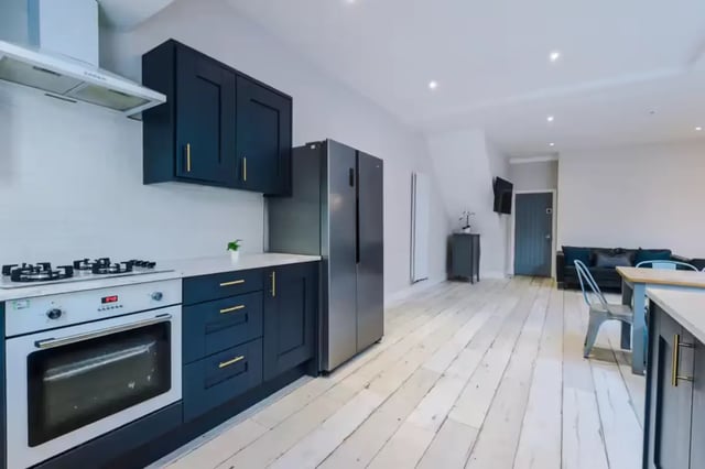 Dark blue cabinets stove fridge and living area kitchen at 86 Woodcroft Road in Liverpool Student Accommodation