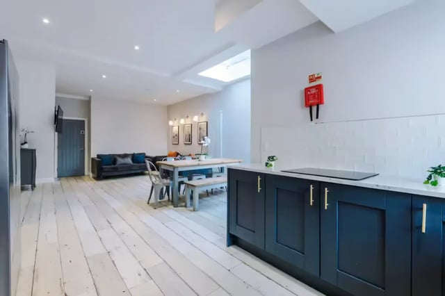 Dark kitchen cabinets with white tiled backsplash and living area Image Type at 86 Woodcroft Road in Liverpool Student Accommodation