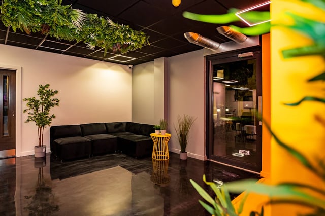 Black sectional sofa yellow table plants living room at Urban Hub in Preston Student Accommodation