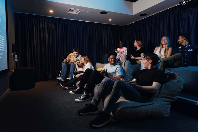 Students watching movie on beanbags and sofa cinema room at Artisan Heights in Manchester Student Accommodation
