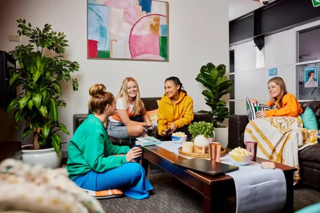 Students relaxing on couch with snacks living room at Mountain x Scape in Sydney Student Accommodation