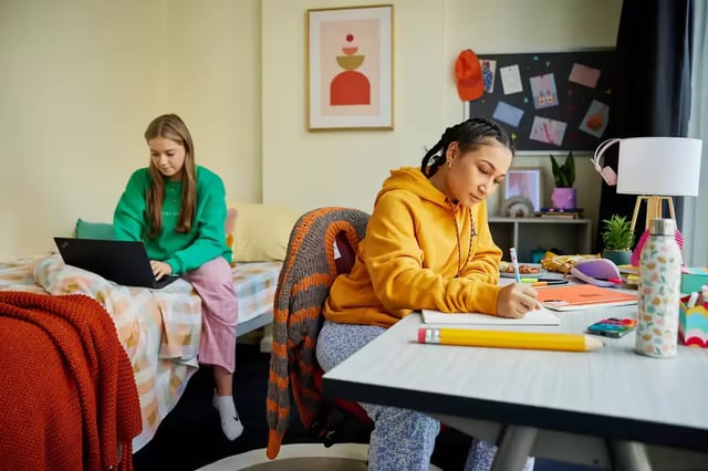 Two students studying laptops and notebooks bedroom at Broadway x Scape in Sydney Student Accommodation