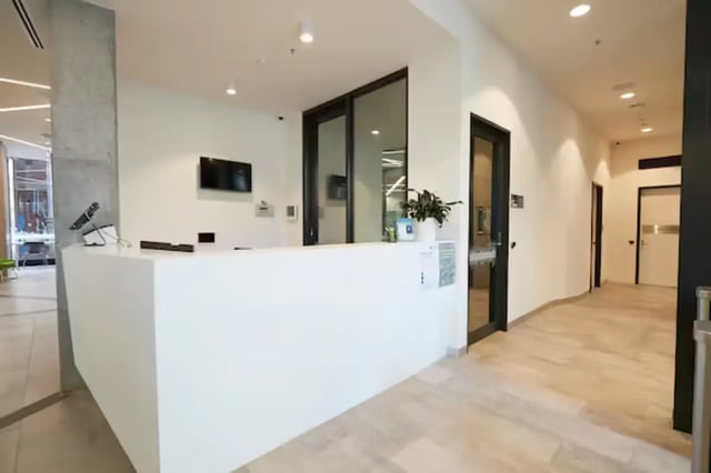White reception desk with monitor and plants reception area at Scape Berkeley 2 in Melbourne Student Accommodation