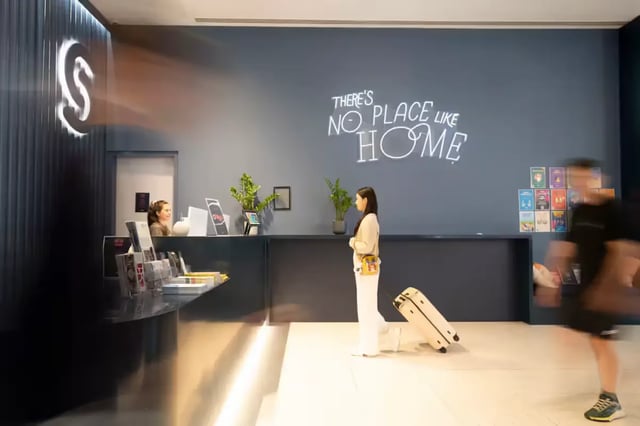 Reception with neon sign and visitors Lobby at Scape Aurora in Melbourne Student Accommodation