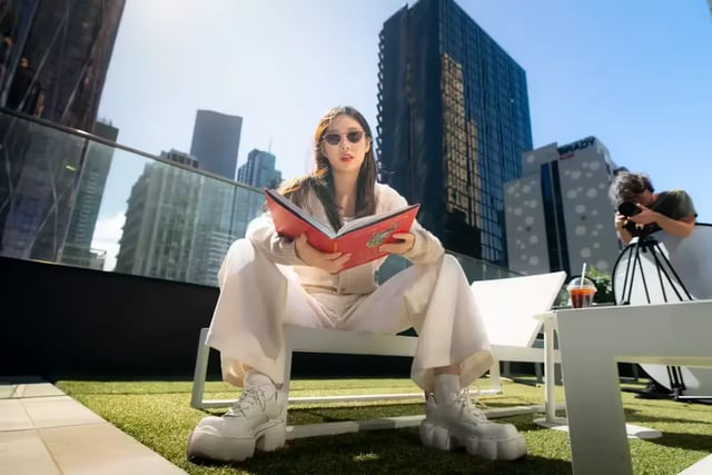Woman reading book on outdoor patio exterior at Scape Aurora in Melbourne Student Accommodation