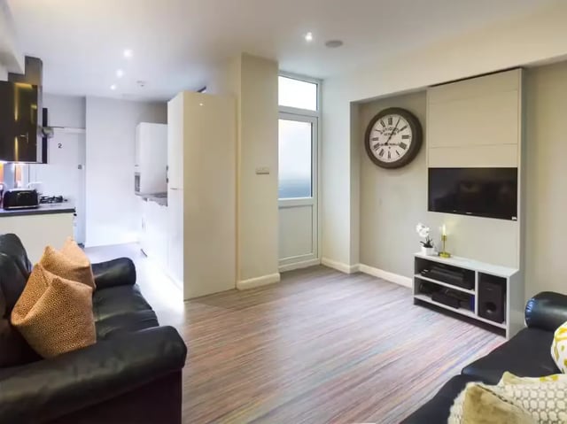 Black sofa patterned pillows wall clock television living room at 233 Leek Road in Stoke-On-Trent Student Accommodation