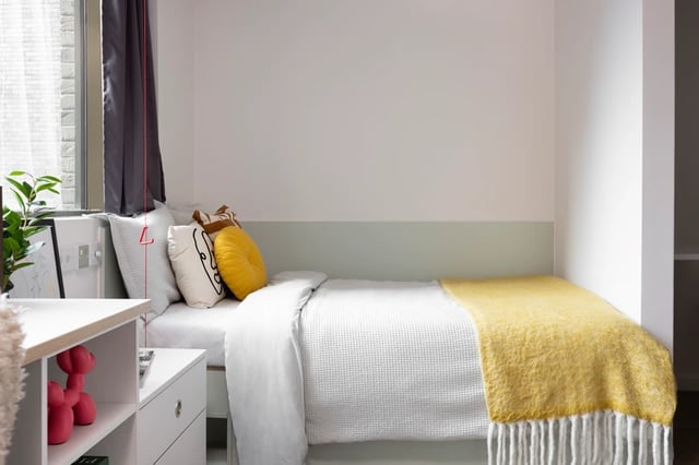 Bed with white linens yellow pillows and throw Bedroom at Bromley Place in Nottingham Student Accommodation