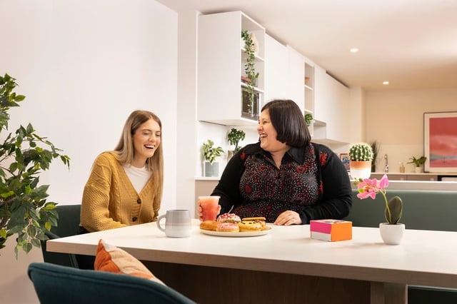 Two women dining area with snacks and drinks Kitchen at Bromley Place in Nottingham Student Accommodation