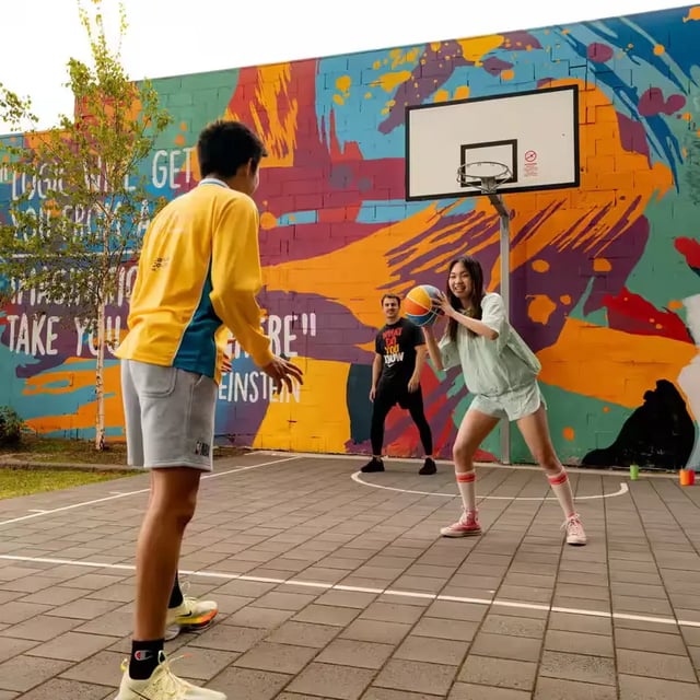 Students playing basketball at colourful court exterior at Scape Waymouth in Adelaide Student Accommodation
