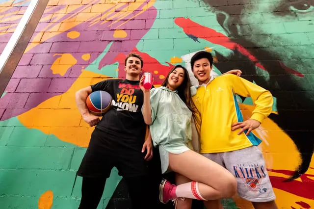 Three friends posing against colorful mural exterior at Scape Waymouth in Adelaide Student Accommodation