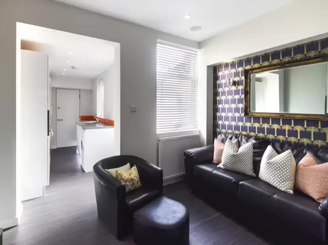 Leather sofa armchair patterned wallpaper living room at 41 Guildford Street in Stoke-On-Trent Student Accommodation